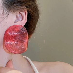 Close-up of a large irregular red resin earring on a model showing translucent texture