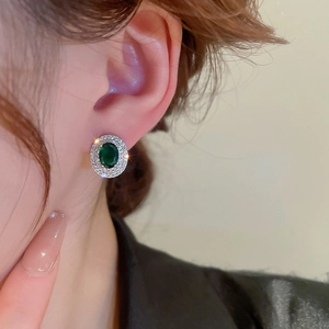 Detail view of emerald oval stud earrings with double halo zircon stones on a model