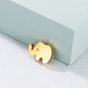 Golden elephant pendant with diamond accent on textured surface next to a teal gift box