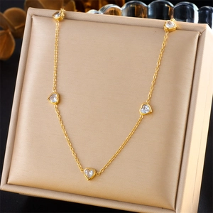 Elegant gold necklace with five heart-shaped clear zircons displayed on a jewelry box