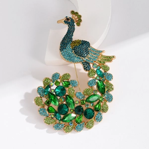 Elegant gold peacock brooch with vibrant multicolored rhinestones on geometric stand