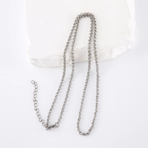 Minimalist stainless steel pearl necklace in silver hanging on a white stone block