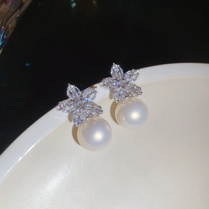 Macro shot of elegant silver flower stud earrings with sparkling crystals and white pearls
