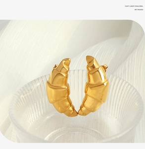 Macro detail of gold croissant earrings with hammered texture on ribbed glass