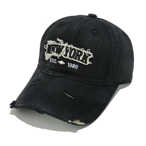 Detail of vintage black baseball cap showing frayed New York embroidery and distressed brim