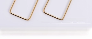 Detailed macro view of high-polished gold rectangular titanium steel hoop earrings