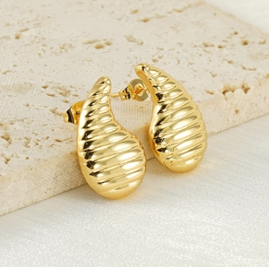 Vue détaillée de boucles d'oreilles goutte dorées avec texture filetée horizontale
