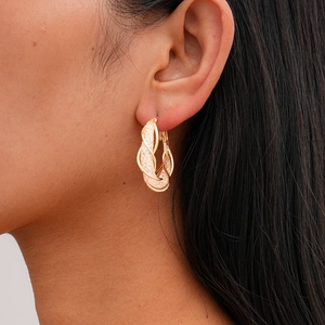Gros plan de la boucle d'oreille dorée torsadée avec texture mate sablée