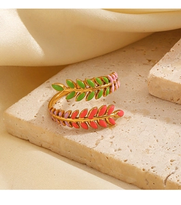 Macro detail of gold-plated leaf ring with green and pink enamel on a stone surface
