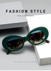 Detail view of oval cat-eye sunglasses with dark green frames and tortoiseshell temples
