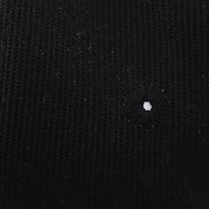 Macro shot of black knit baseball cap fabric texture with white embroidered vent eyelet