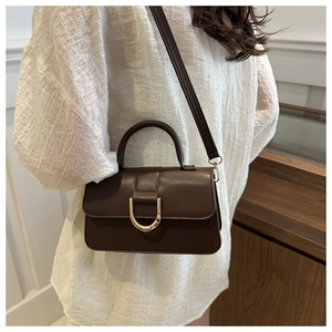 Detail of dark brown PU leather handbag featuring a signature gold horseshoe buckle