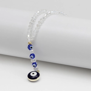 Detailed view of evil eye pendant with crystal beads on a white minimalist pedestal
