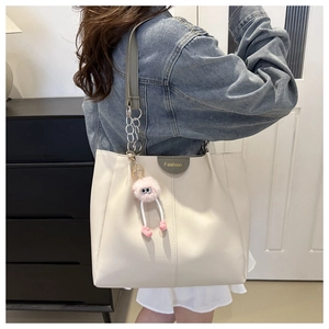 Vista posteriore della modella con borsa tote crema, catena in metallo e charm in peluche