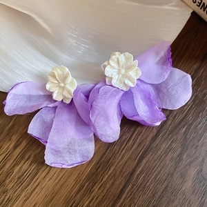 Detail of purple fabric floral earrings with layered petals and white pearl center