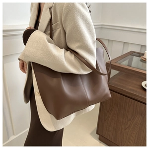 Detail of dark brown leather tote bag showing vertical seam design on a model