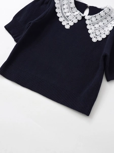 Detailed view of the dark knit top featuring a delicate white floral lace collar and ribbing
