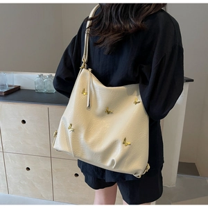 Detail of off-white PU leather hobo bag featuring gold butterfly ornaments and adjustable strap