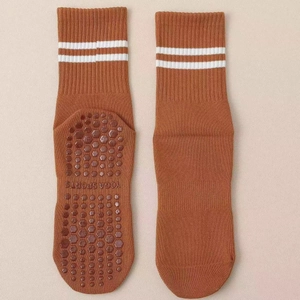 Detailed view of brown yoga socks with white stripes and hexagonal non-slip grip soles