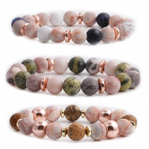 Tre braccialetti minimalisti con perline in pietra naturale e dettagli in metallo su fondo bianco