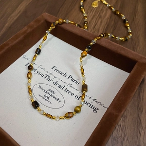 Détail du collier en œil de tigre avec perles d'ambre dans un écrin à bijoux