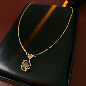 Detail of gold-plated butterfly necklace with green zircon pendant on black leather box