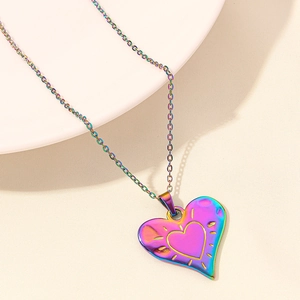 Detailed macro of a rainbow plated heart pendant necklace with ray engravings on chain