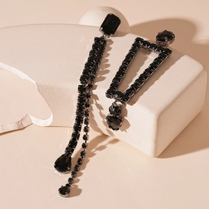 Macro detail of asymmetric black rhinestone drop earrings with dark metal geometric design