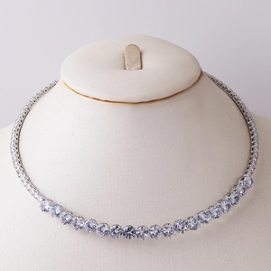Close-up of a silver tennis necklace with sparkling cubic zirconia on a beige bust