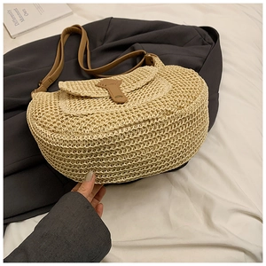 Detail of hand-woven beige straw texture with brown leather strap and buckle closure
