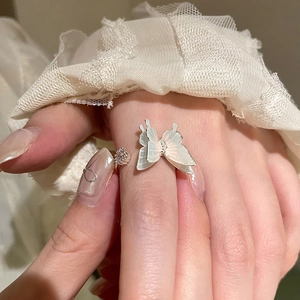 Detailed view of silver butterfly ring with mother of pearl wings on lace background