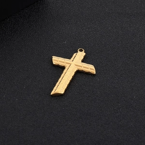 Macro shot of a golden twisted cross pendant with textured pattern and top loop detail