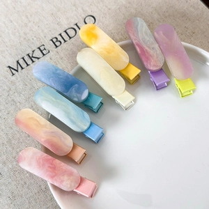 Detail view of 8 colorful marble glitter jelly duckbill hair clips on a white plate
