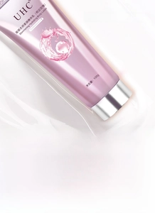 Detail of hydrating body cream tube in pink gradient on a fluid white cream texture