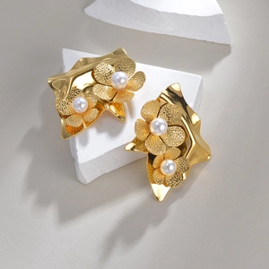 Elegant gold flower petal earrings with pearls on a minimalist geometric stone display