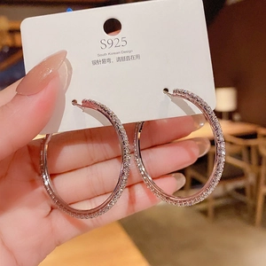 Macro detail of silver S925 needle hoop earrings with pavé set sparkling zircon stones
