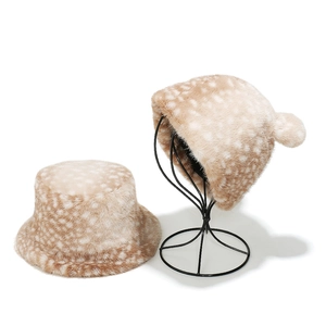 Winter faux fur bucket hat with reindeer pattern displayed on a metal stand