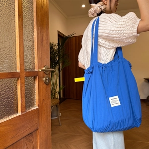 Detailed view of deep blue striped drawstring tote bag with branding on a shoulder strap