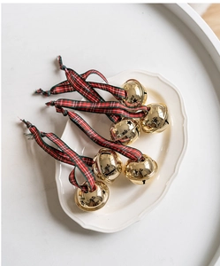 Close-up of golden Christmas bells with star cutouts and red-green plaid ribbons