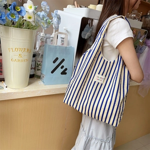 Close-up of yellow and blue striped seersucker tote bag worn by model in a flower shop