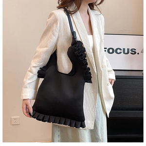 Detail of the black shoulder bag featuring ruffled edge design and a modern aesthetic