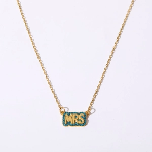 Detailed macro view of golden MRS pendant with blue zircon stones on a fine chain