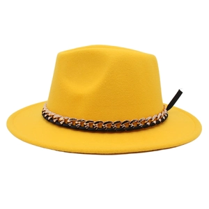 Macro detail of a yellow felt fedora hat featuring a gold and black chain decorative band