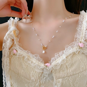Détail d'un collier vintage doré en titane avec perle baroque et fermoir en T