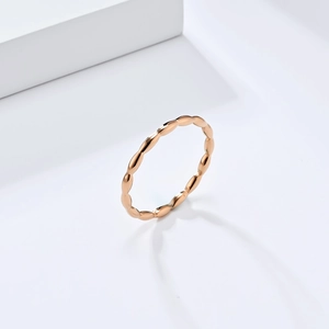 Detailed macro view of a rose gold beaded stainless steel ring on a white platform