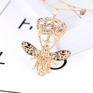 Détail d'une broche abeille avec couronne dorée, strass brillants et perle élégante