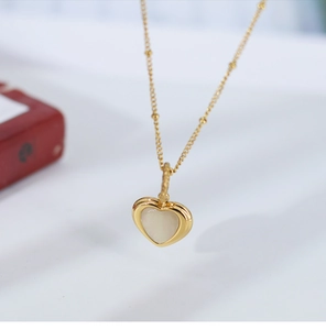 Macro shot of gold heart necklace with elegant white mother of pearl inlay detail