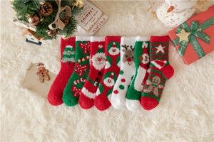 Flat lay of thick Christmas coral fleece socks with festive patterns on white faux fur