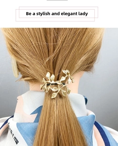Detail of golden leaf-shaped ponytail hook showing intricate embossed metal textures