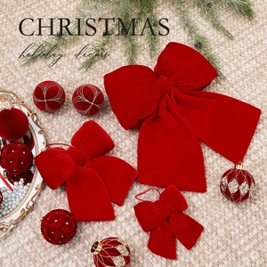 Red velvet Christmas bows and matching ornaments on a beige textured knit background